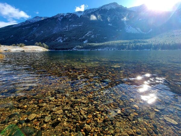 A clear mountain lake with visible stones under a sunny sky—Mystic Lake, Montana.